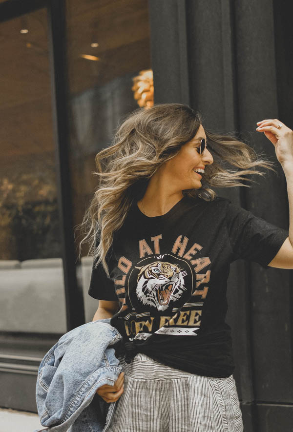 Girl standing on sidewalk wearing a graphic tee shirt, pants and a jean jacket