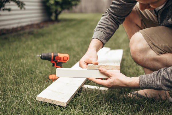 Guy holding a piece of wood for a raised garden bed