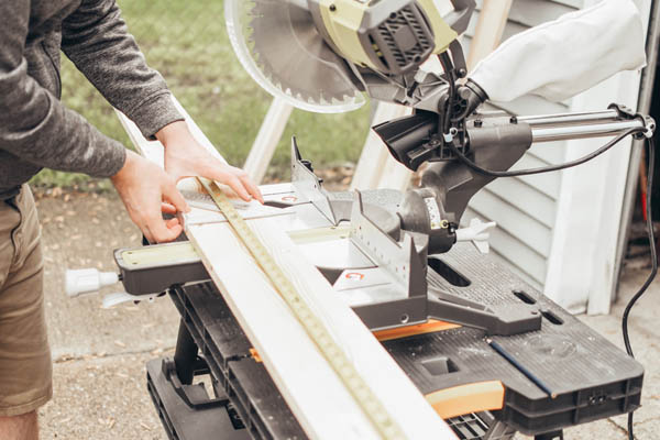 Man cutting wood for raised garden bed