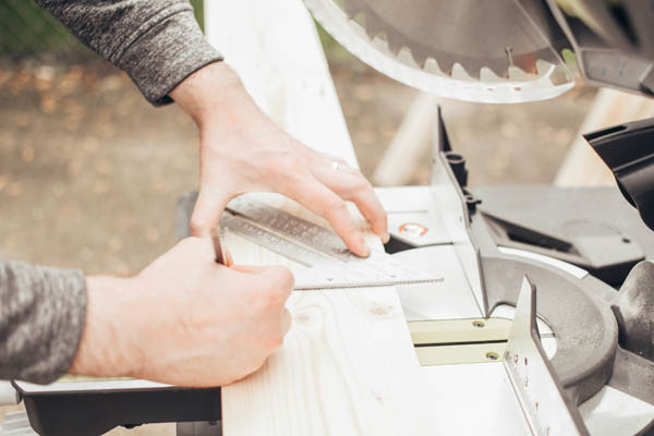 Man measuring and cutting wood for a raised garden bed