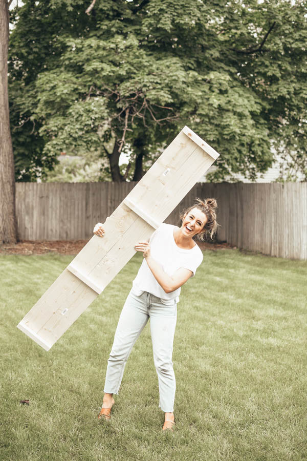 girl holding a piece of wood for a raised garden bed